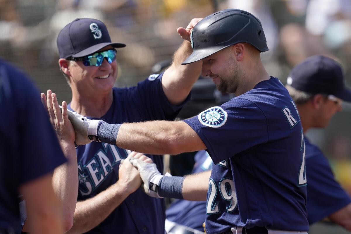 Seattle Mariners' Cal Raleigh, right, is congratulated by manager Scott Servais after hitting a two-run home run against the Oakland Athletics during the fifth inning of a baseball game in Oakland, Calif., Thursday, Sept. 23, 2021. (AP Photo/Jeff Chiu)