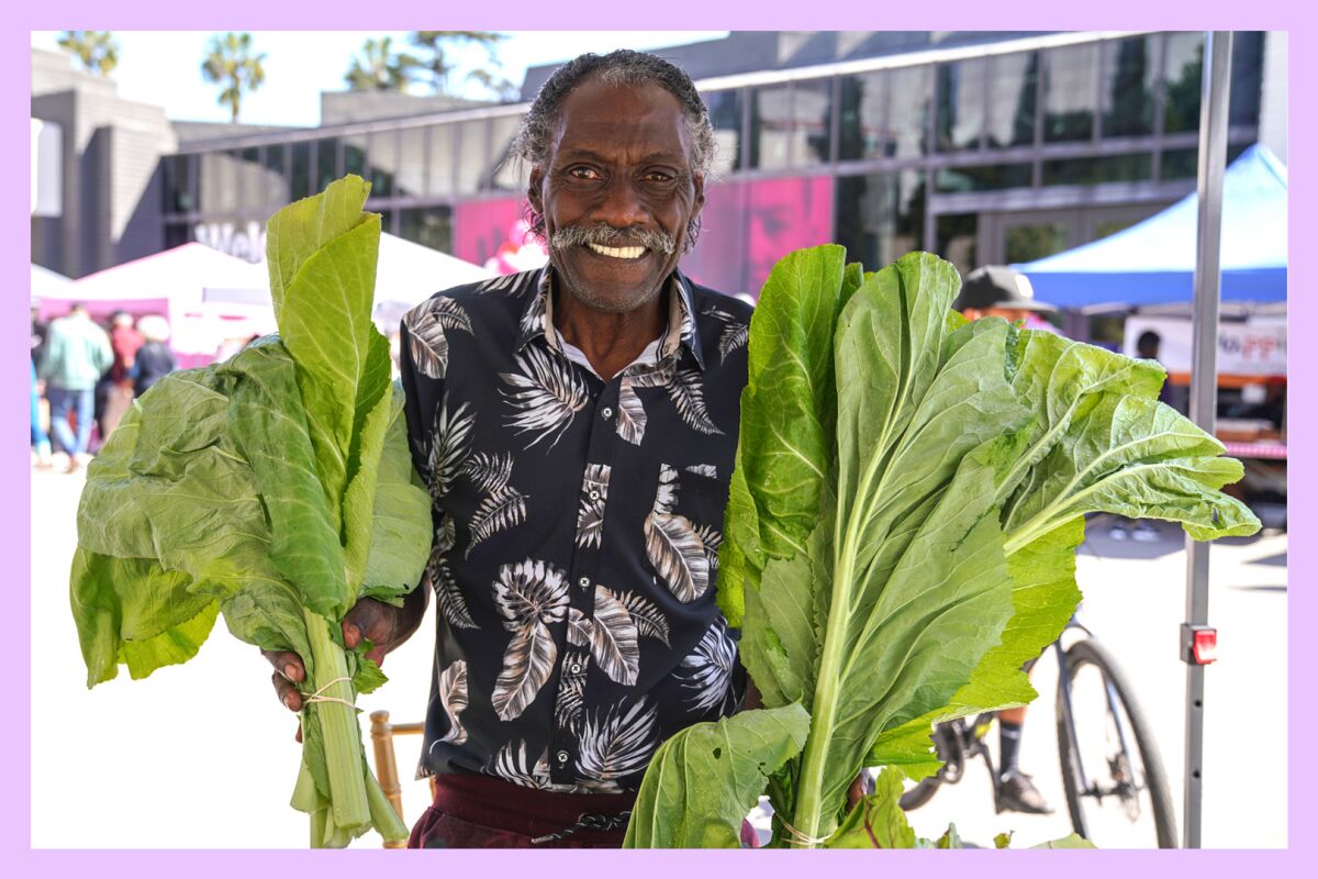 A man holds two large green leafy vegetables