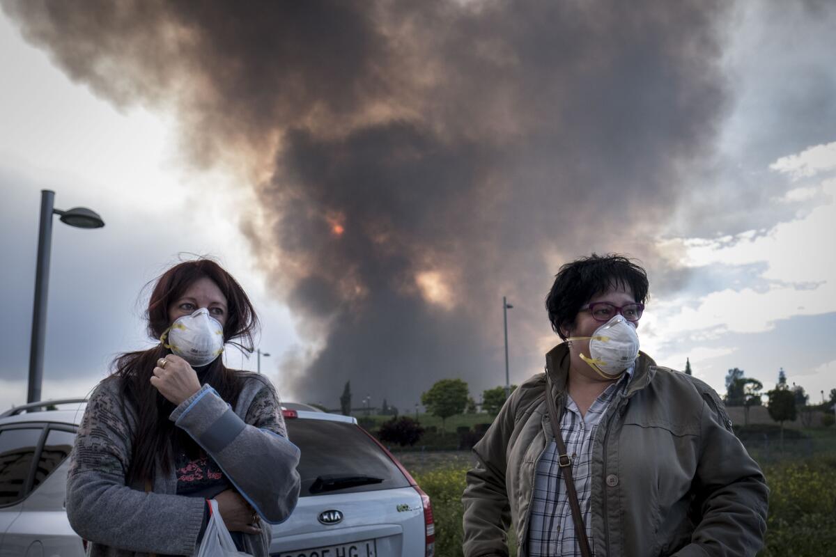 Two residents of Sesena, Spain, wait Friday for other relatives to evacuate an area affected by the toxic fumes produced by burning tires.
