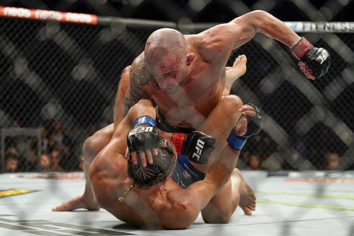 Alexander Volkanovski, top, punches Brian Ortega during a featherweight mixed martial arts title bout at UFC 266, Saturday, Sept. 25, 2021, in Las Vegas. (AP Photo/John Locher)
