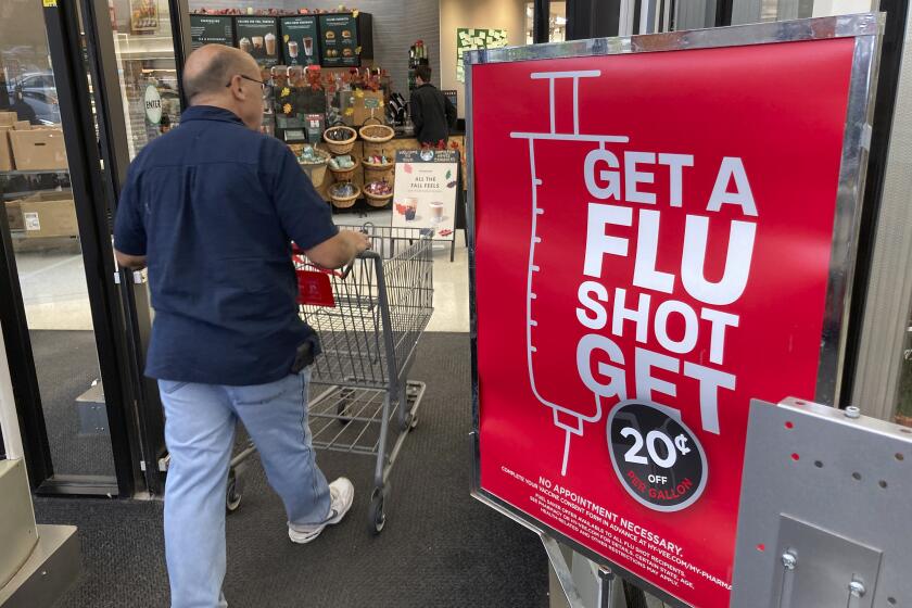 A shopper passes a sign urging people to get a flu shot outside a Hy-Vee grocery store in Sioux City, Iowa.