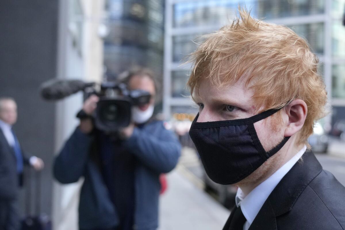 A red-haired man whose face is covered by a black fabric mask