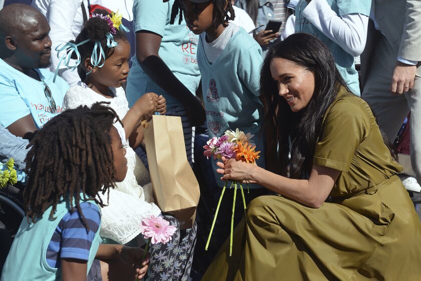 FILE - In this Sept, 24, 2019, file photo, Meghan, the Duchess of Sussex, talks to children during a walkabout in Bo-Kaap, a heritage site, in Cape Town, South Africa. In countries with historic ties to Great Britain, allegations by Prince Harry and Meghan about racism within the royal family have raised questions about whether those nations want to be closely connected to Britain anymore after the couple's interview with Oprah Winfrey. (Courtney Africa/Pool via AP, File)
