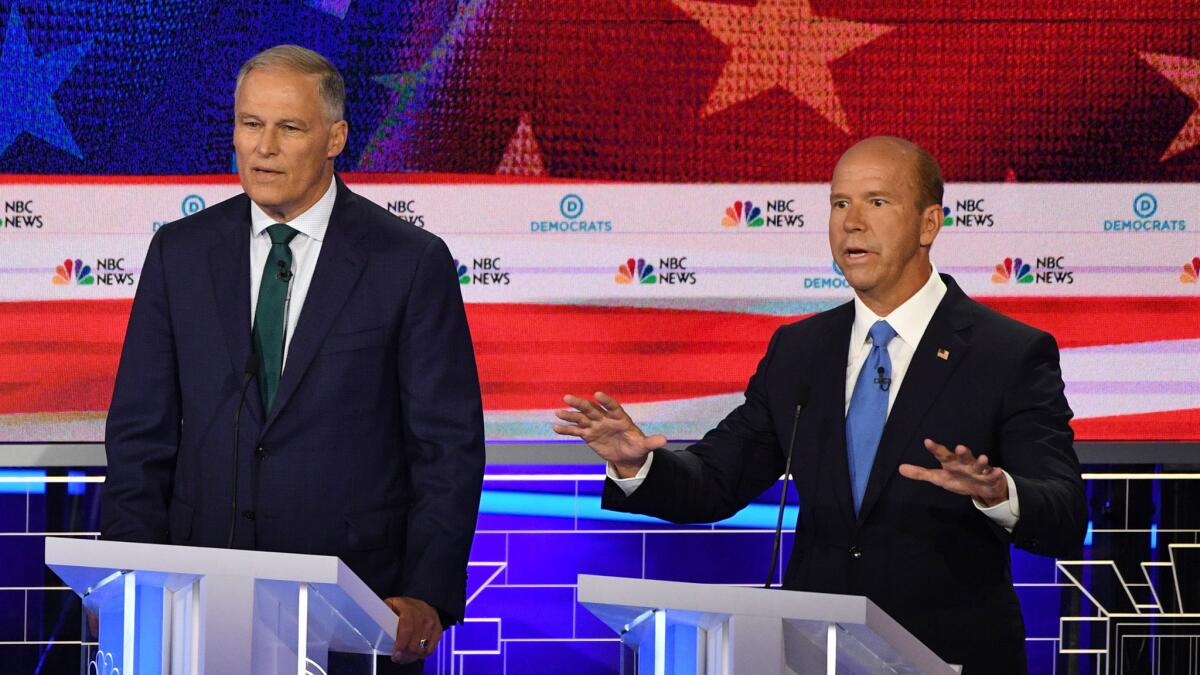 Flanked by Washington Gov. Jay Inslee to his right, former Rep. John Delaney (D-Md.) speaks during Night 1 of the Democratic primary debate in Miami. (Jim Watson / AFP/Getty Images)
