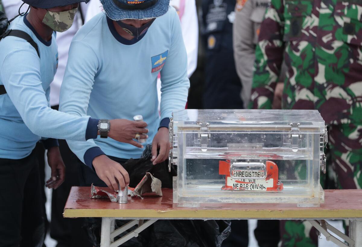 Indonesian navy personnel handle a box containing the flight-data recorder from a plane that crashed in the Java Sea.
