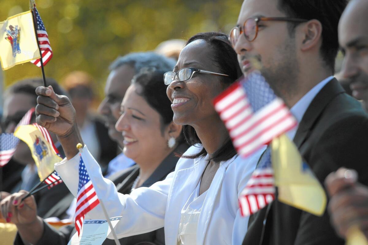 New American citizens wave flags after taking the oath of citizenship at Liberty State Park in Jersey City, N.J.