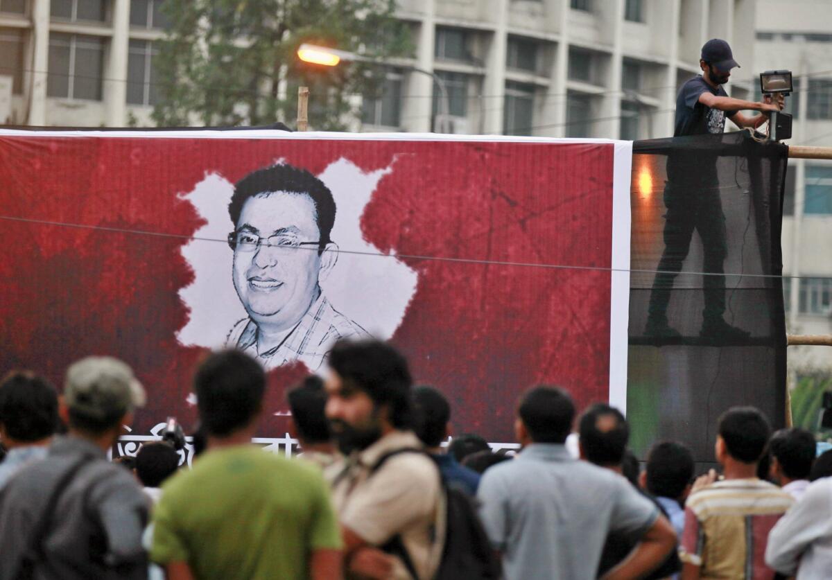 A Bangladeshi activist sets up a light on a poster displaying a portrait of Avijit Roy as others gather during a Feb. 27 protest over the blogger's slaying in Dhaka the night before.