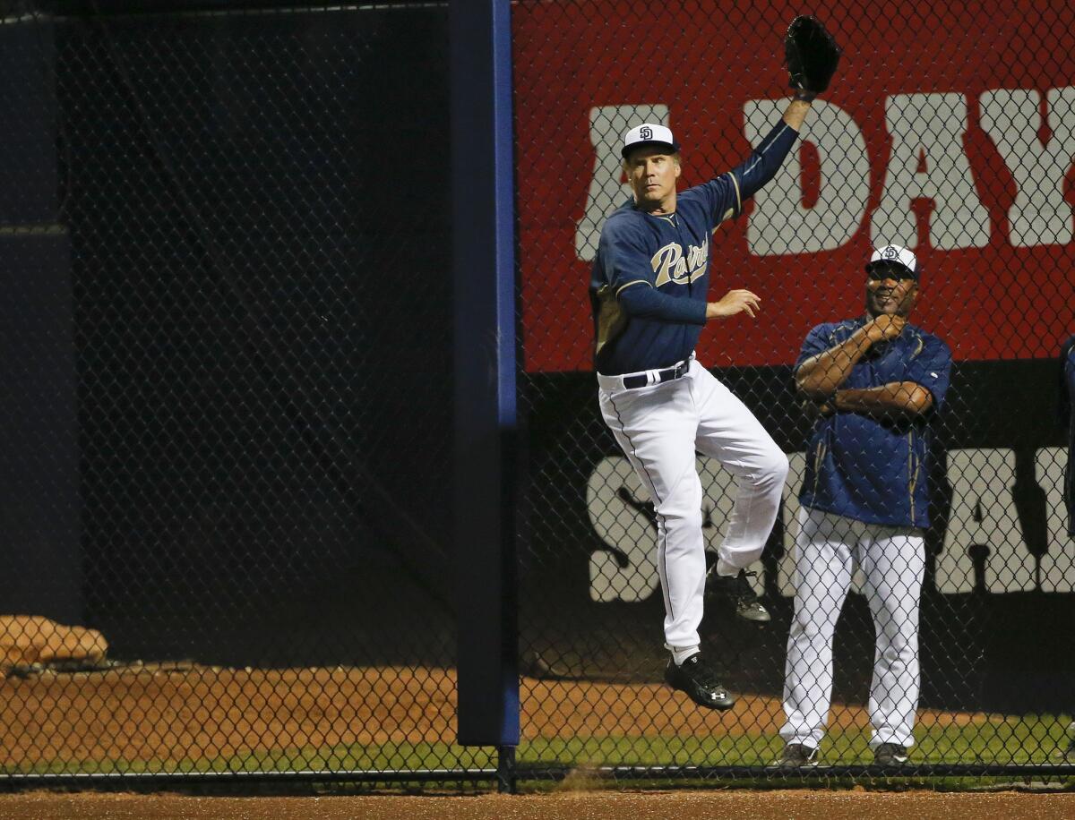 Actor Will Ferrell jumps at the right field fence on a home run from Dodgers outfielder Joc Pederson while playing for the San Diego Padres during a spring training game in Peoria, Ariz.