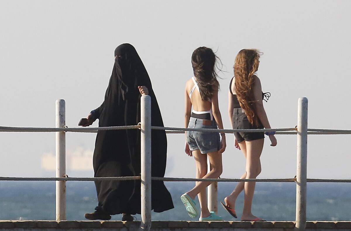 FILE - In this July 26, 2019 file photo, holiday makers walk at al Sokhna beach in Suez, Egypt. The burkini, a swimsuit worn by conservative Muslims to cover the entire body, is scorned in many upper class Egyptian circles where it and the headscarf is seen as lower class. Women who wear the burkini or headscarves can face discrimination in upper-class beach resorts or in bars or clubs, though across Egypt the majority of women wear conservative dress. (AP Photo/Amr Nabil)