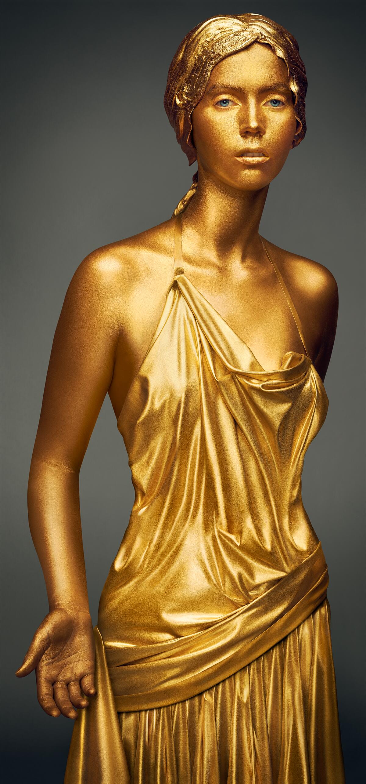 A woman in a metallic dress painted in all gold