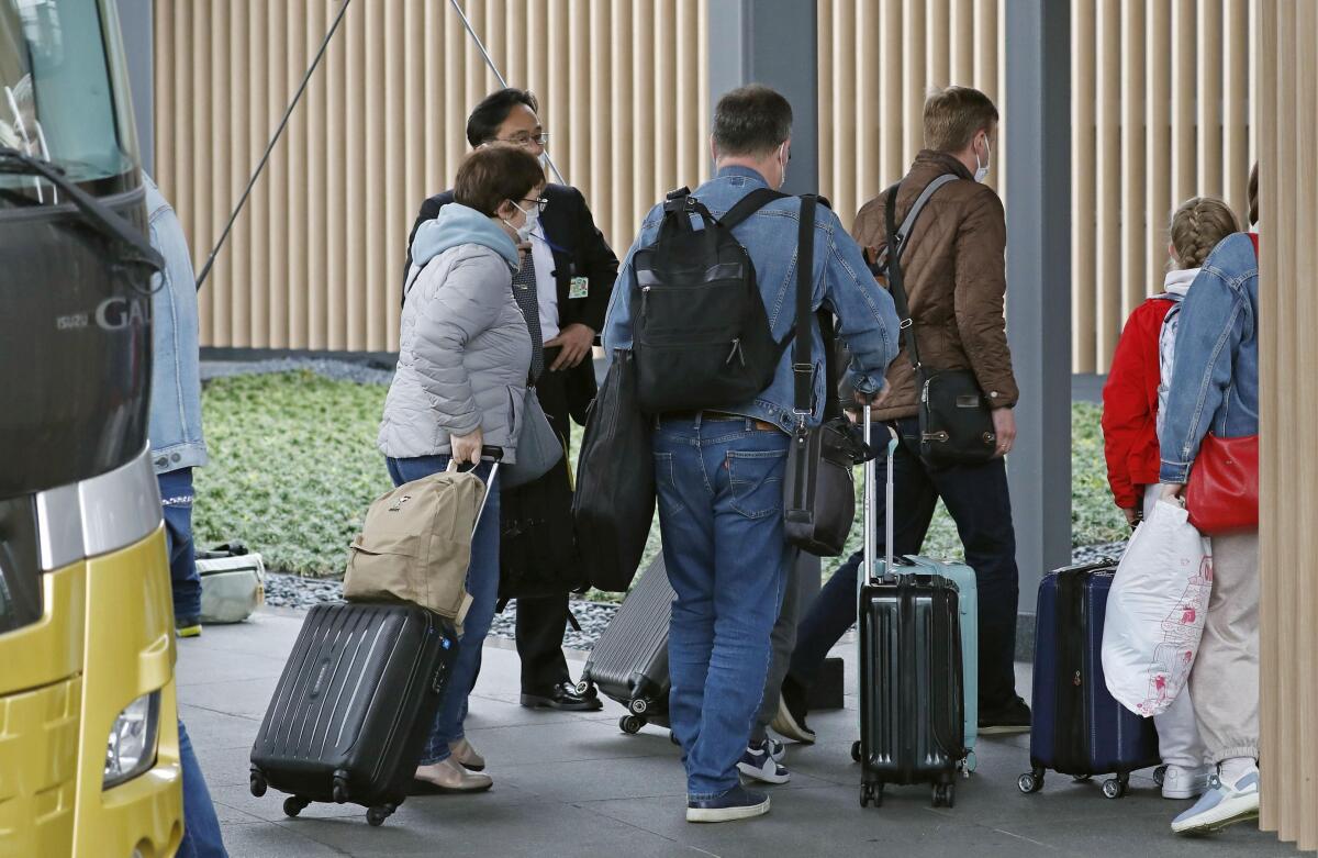 People who left Russian Embassy arrive at the Haneda international airport, in Tokyo, Wednesday, April 20, 2022. On Wednesday, the eight Russian diplomats subject to expulsion were seen leaving the Russian embassy in Tokyo on a bus to the international airport, where they took a Russian government plane back to their country. (Kyodo News via AP)