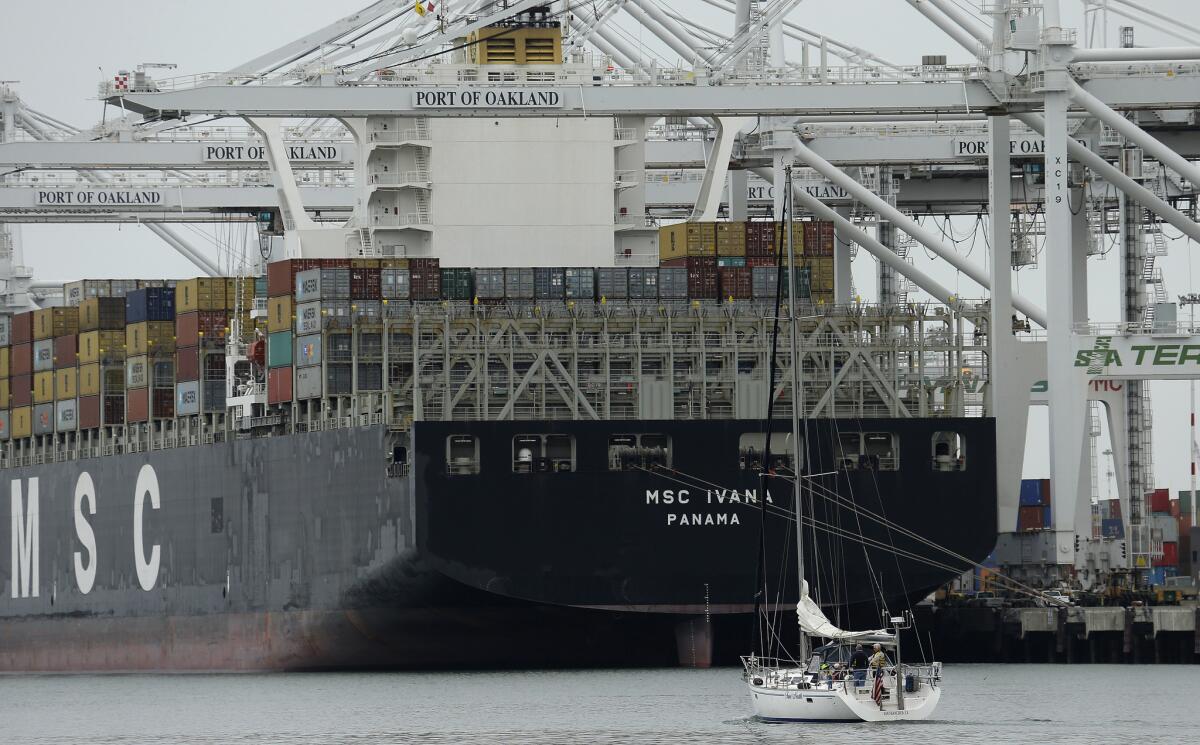 A sailboat makes its way past the container ship MSC Ivana as it is unloaded at the Port of Oakland on March 3.