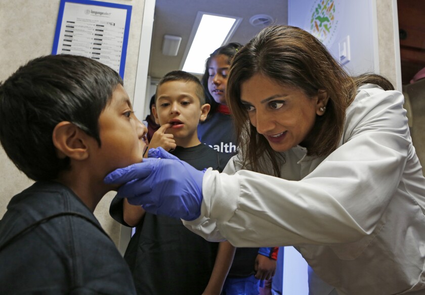 Dr. Roshani Mehta gives David Munoz, 7, a check-up at a mobile clinic at Rosewood Park Elementary in Los Angeles. A new poll has found that likely voters are less likely than all adults to support expanding healthcare coverage to those in the U.S. illegally.