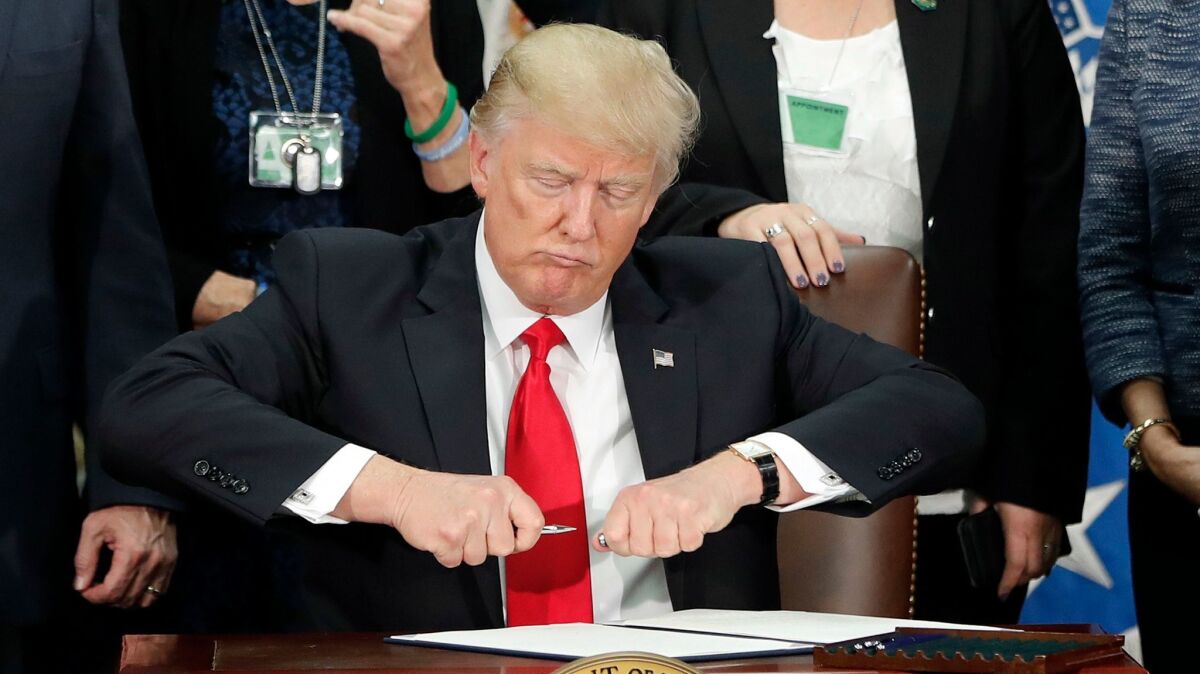 President Donald Trump takes the cap off a pen before signing an executive order for immigration actions to build a border wall in Washington on Jan. 25.