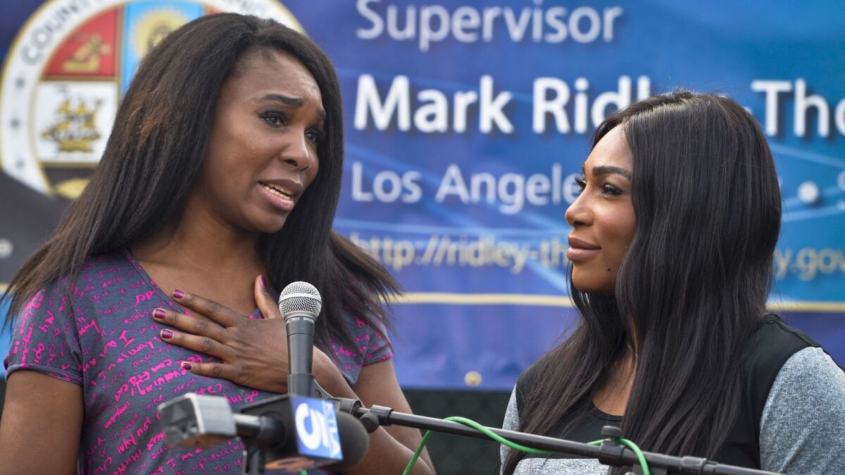 Venus Williams, left, and sister Serena Williams speak at the opening ceremony for new tennis courts in Compton.