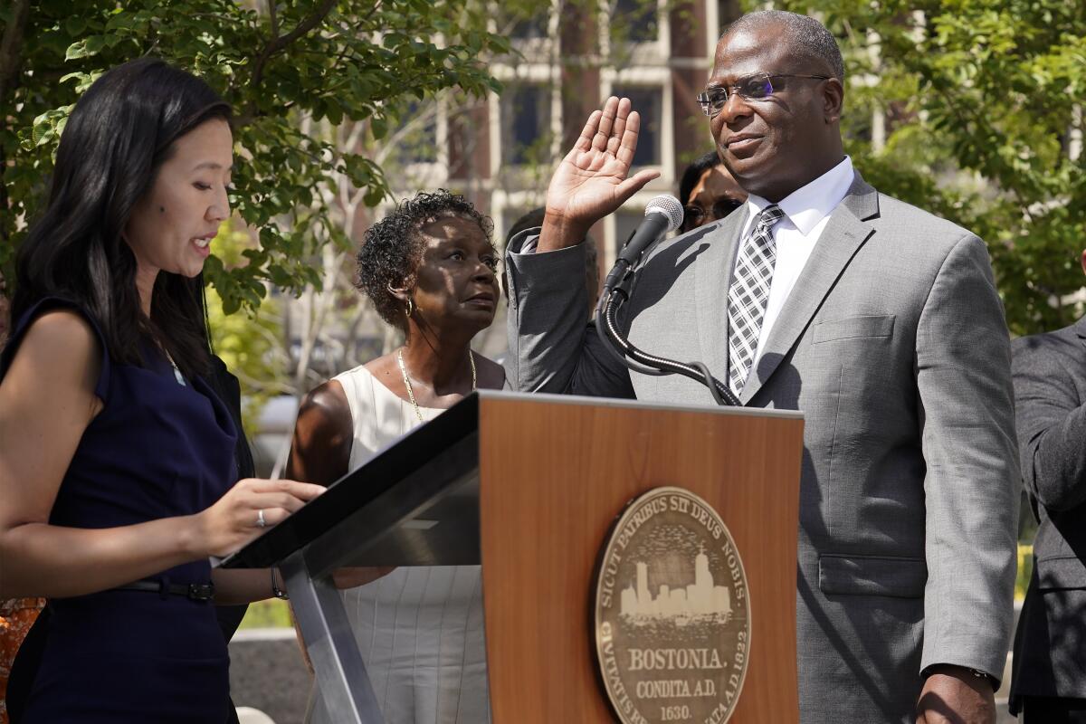 Michael Cox, right, raises his hand as he is sworn in as commissioner of the Boston police department by Mayor Michelle Wu, left, Monday, Aug. 15, 2022, in Boston. Cox, a Boston police veteran, was brutally beaten by fellow officers while chasing a suspect and fought against efforts to cover up his assault. (AP Photo/Steven Senne)