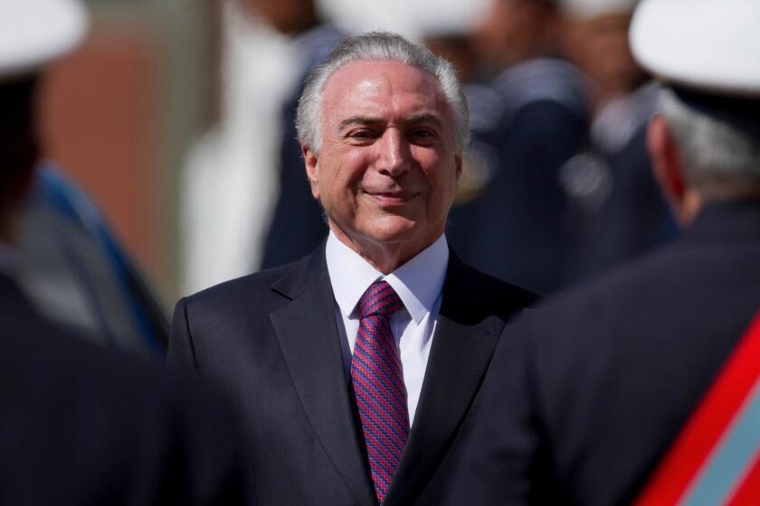 Brazil's President Michel Temer smiles as he receives military honors during ceremony, in Brasilia, Brazil, Friday, June 9, 2017. Brazil's top electoral court has decided to keep embattled President Temer in office. Judges on the Supreme Electoral Tribunal voted 4-3 against a suit about alleged campaign finance violations that would have annulled what was left of Temer's mandate. The decision is a much needed victory for Temer, who has faced growing calls that he resign amid a corruption scandal. (AP Photo/Eraldo Peres)