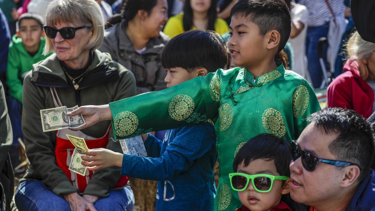 Tyson Tran, 7, right, offers a gift to a dancing lion at the Tet Festival.