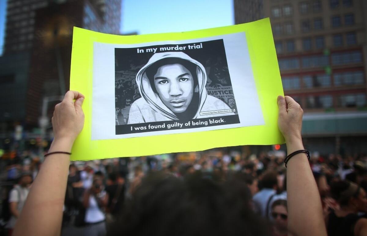 A protester holds a sign at a rally honoring Trayvon Martin in New York on Sunday. On Saturday, George Zimmerman was acquitted in the shooting death of Martin.