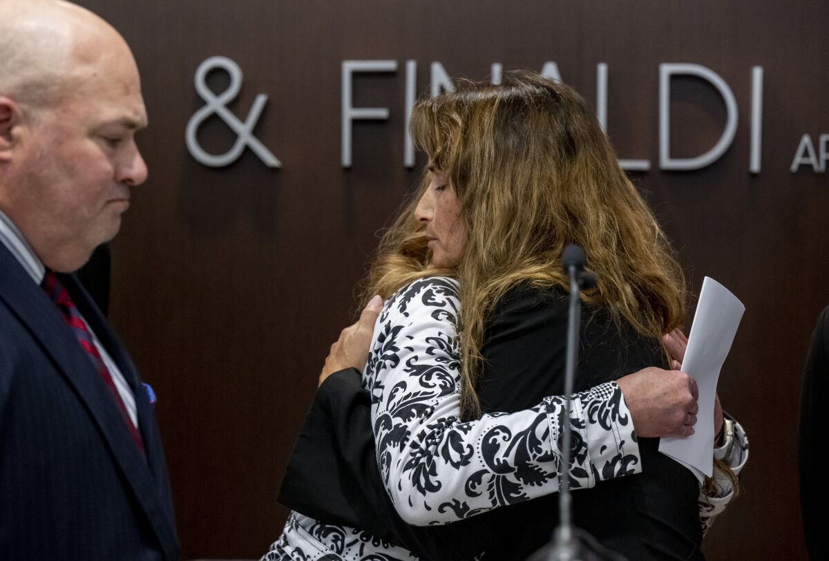 Survivors Kara Cagle, center, and Julie Wallach embrace during a news conference where attorney John Manly, left, announced a $243-million settlement in the UCLA sex abuse case of former UCLA gynecologist/oncologist James Heaps, at the law offices of Manly, Stewart & Finaldi in Irvine, Calif., Tuesday, Feb. 8, 2022. (Leonard Ortiz/The Orange County Register via AP)