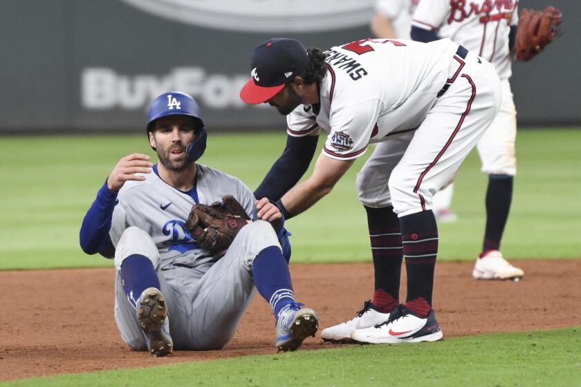Atlanta, GA - October 16: Atlanta Braves shortstop Dansby Swanson, right, tags out Los Angeles Dodgers' Chris Taylor.
