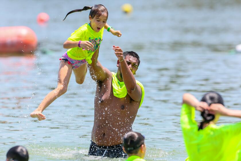 San Dimas, CA, Thursday, July 25, 2024 - Arcadia Summer Camp counselor Jamaal Saldin serves as a launching pad for young campers during an outing at Bonelli Park's swim beach at Puddingstone Reservoir. (Robert Gauthier/Los Angeles Times)