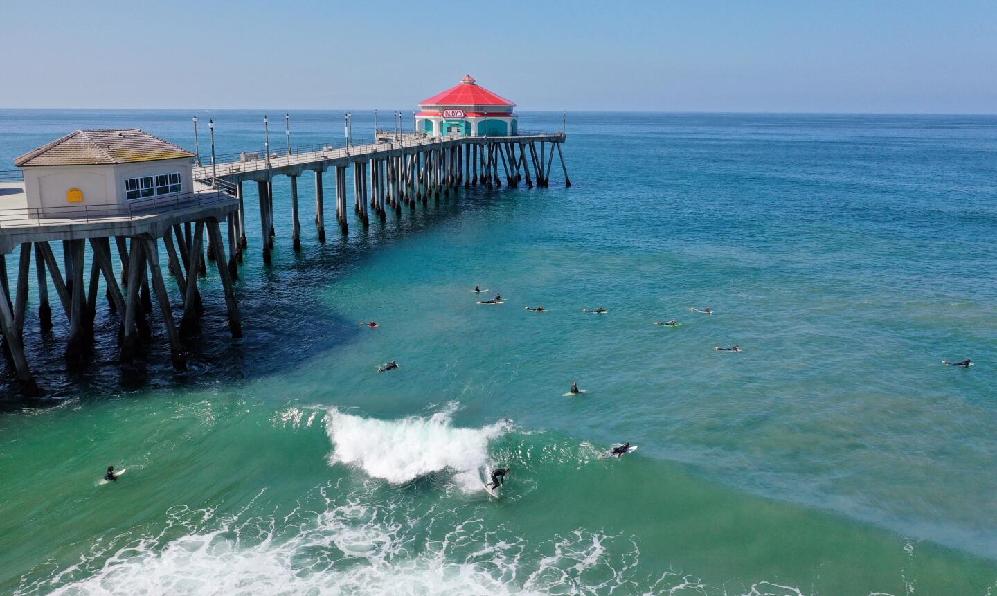 Surfers ride the waves on the north side of the Huntington Beach Pier