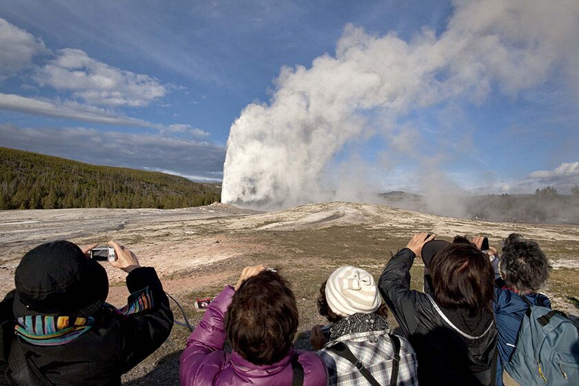 Tourists photograph Old Faithful erupting at Yellowstone National Park, Wyo., in 2011.