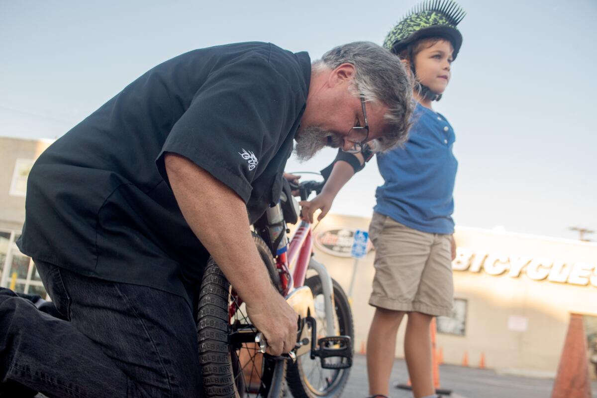 Jax Bicycle Center manager Jesse May tunes up Bentley William's bike during a Huntington Beach Bike Rodeo.