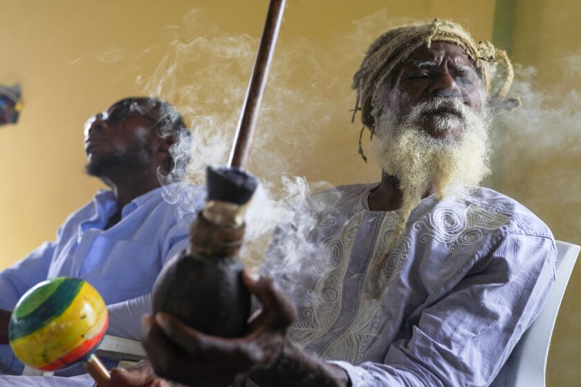 Ras Jah, a member of the Ras Freeman Foundation for the Unification of Rastafari, prepares to pass a chalice pipe with marijuana to the left during service in the tabernacle on Sunday, May 14, 2023, on the Ras Freeman Foundation for the Unification of Rastafari property in Liberta, Antigua. The Rastafari faith is rooted in 1930s Jamaica, growing as a response by Black people to white colonial oppression. The beliefs are a melding of Old Testament teachings and a desire to return to Africa. (AP Photo/Jessie Wardarski)