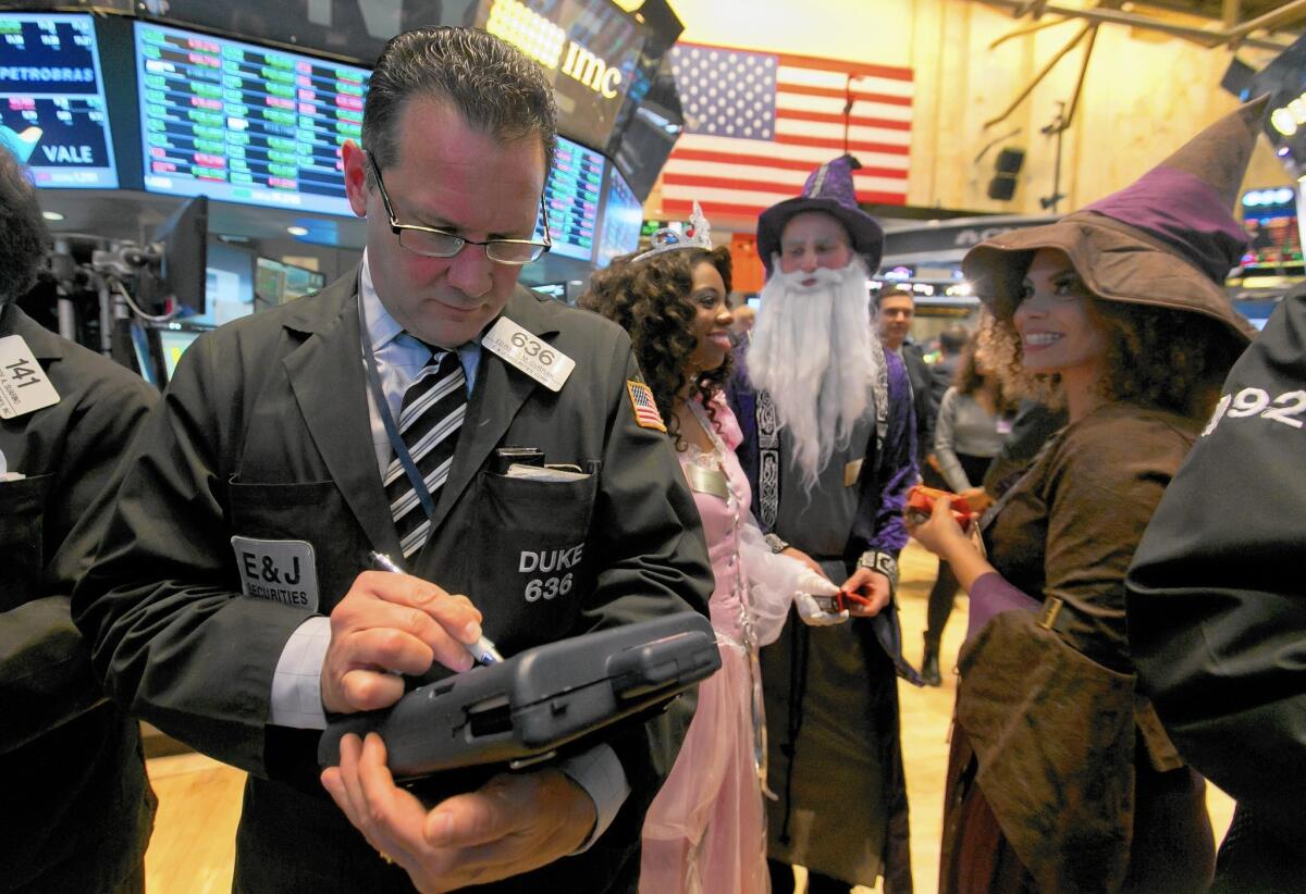 Trader Edward Curran works the New York Stock Exchange floor as costumed characters offer candy on Halloween, when stocks rallied worldwide.