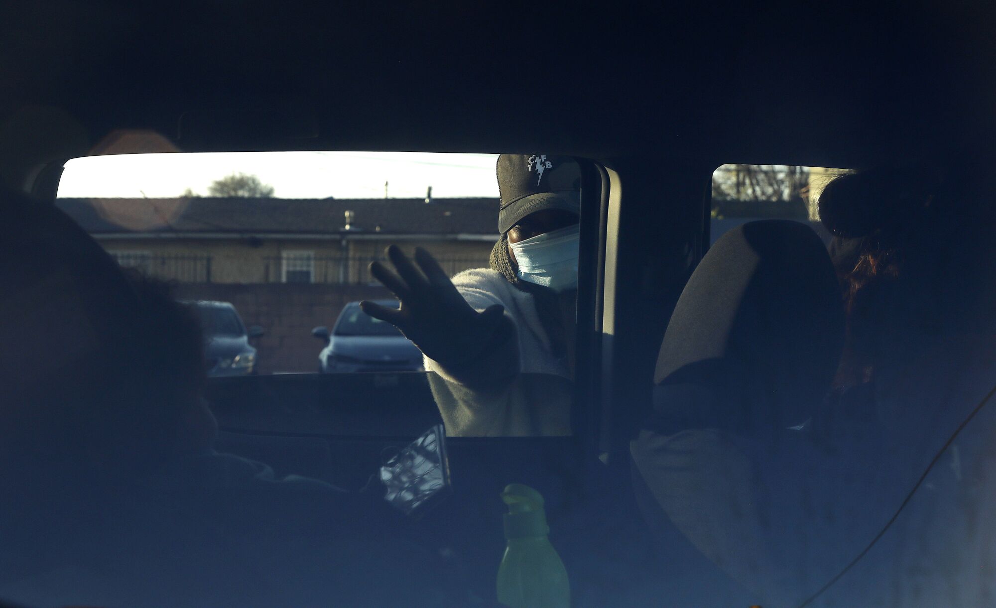 Church secretary Shanicka Oten waves to a child in the back seat during the food giveaway.