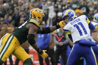 Packers linebacker Rashan Gary (52) grabs the face mask of  Rams quarterback Brett Rypien.