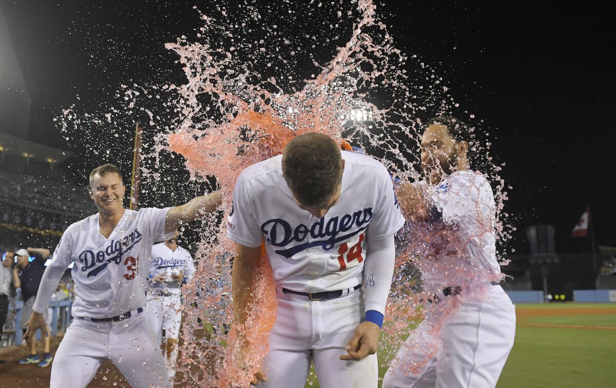 Los Angeles Dodgers' Enrique Hernandez, center, is doused by Chris Taylor, left, and Russell Martin after driving in the winning run during the ninth inning of the team's baseball game against the Toronto Blue Jays on Thursday, Aug. 22, 2019, in Los Angeles. (AP Photo/Mark J. Terrill)
