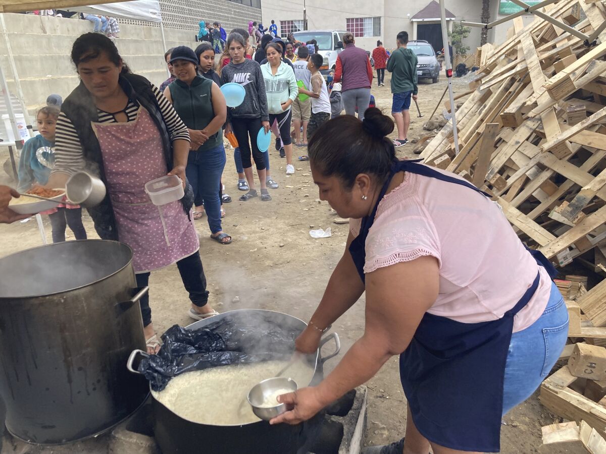 A woman serves dinner of rice and beans to migrants.