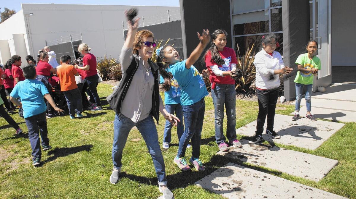 Newport Mesa Unified School District Board Member Karen Yelsey, left, joins a Whittier Elementary School fourth graders in throwing mud balls during an Earth Day celebration at Newport Banning Land Trust in Costa Mesa on Tuesday.