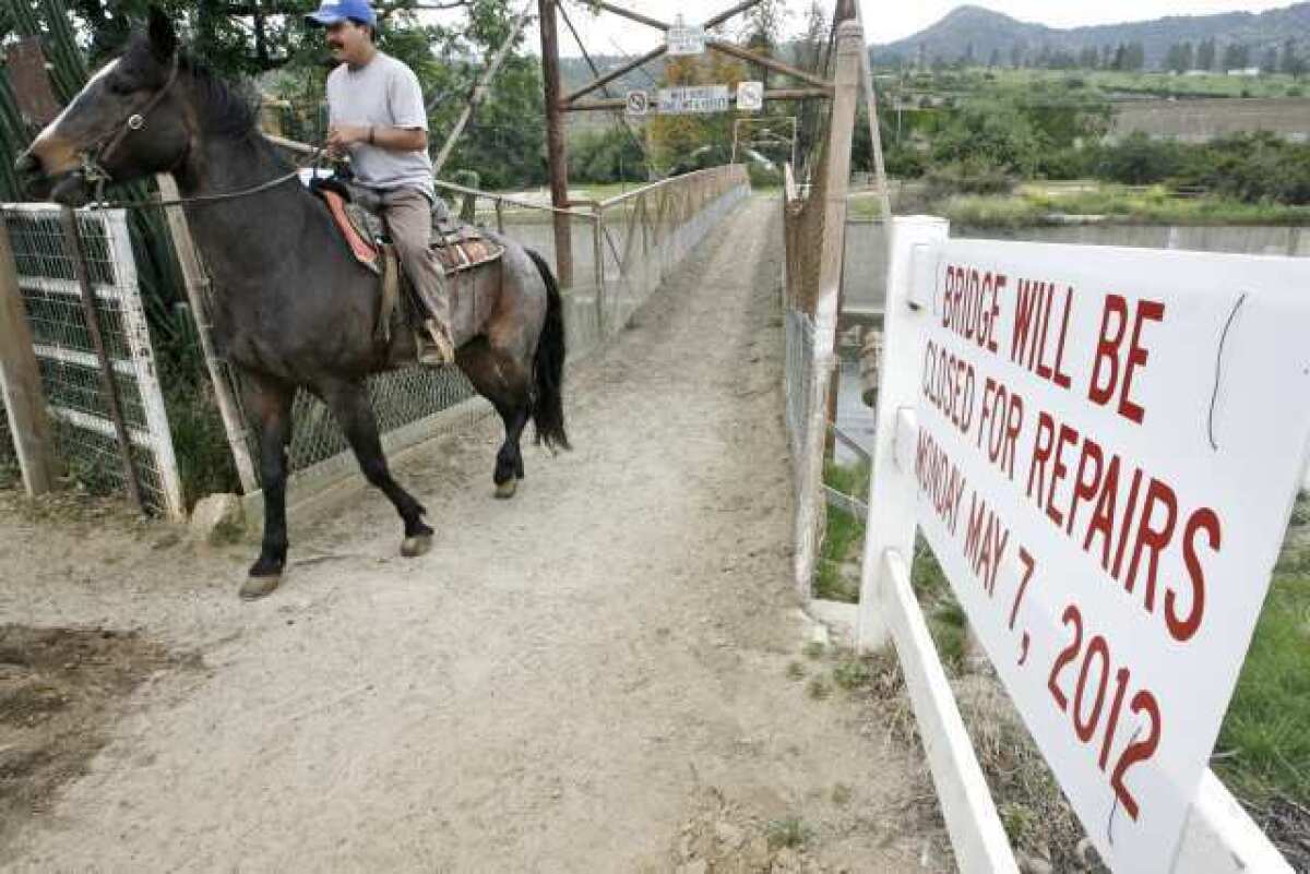 Wrangler Melesio Ochoa rides a horse back to the stables over the Mariposa Street bridge. The bridge is scheduled to be closed on Monday for repairs.