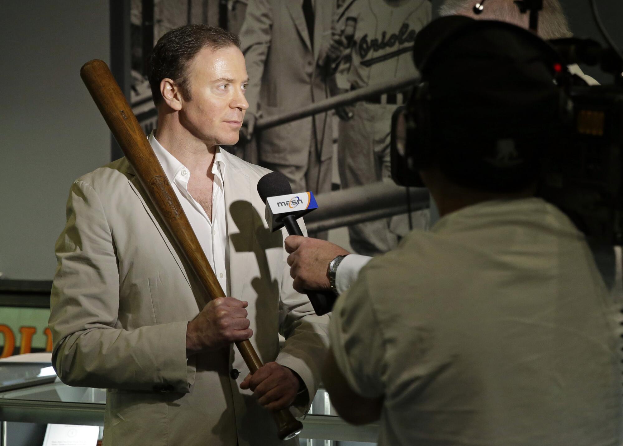 Goldin Auctions founder Ken Goldin holds a baseball bat