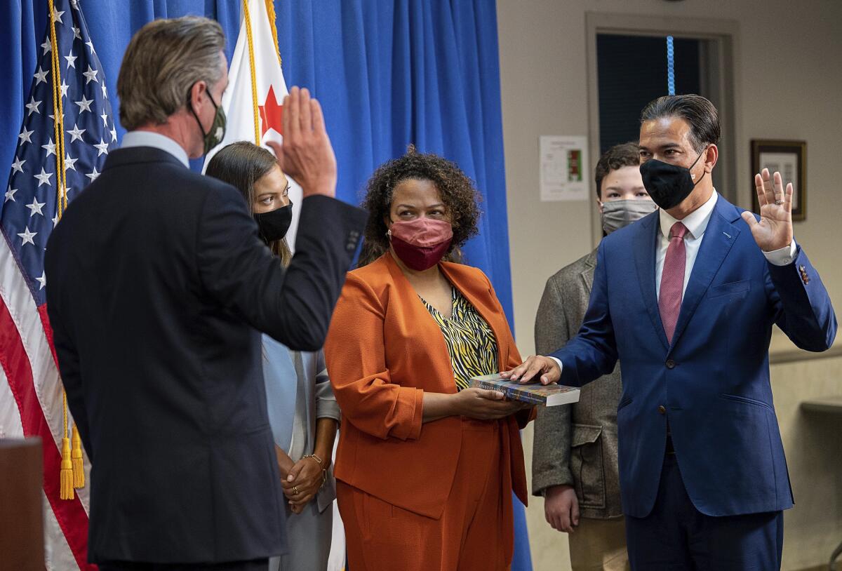 Assemblyman Rob Bonta, right, is sworn in as attorney general by Gov. Gavin Newsom as his wife, Mia Bonta, holds a book.