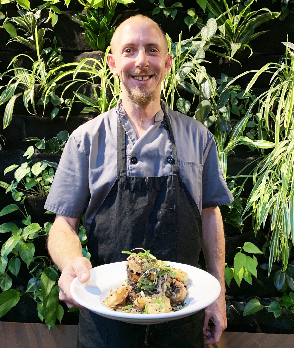Mario Manship, the executive chef at Masters Kitchen and Cocktail in Oceanside, with one of the dishes on his new menu rolling out Nov. 1: honey pecan shrimp with forbidden black rice and fried pork belly bites.