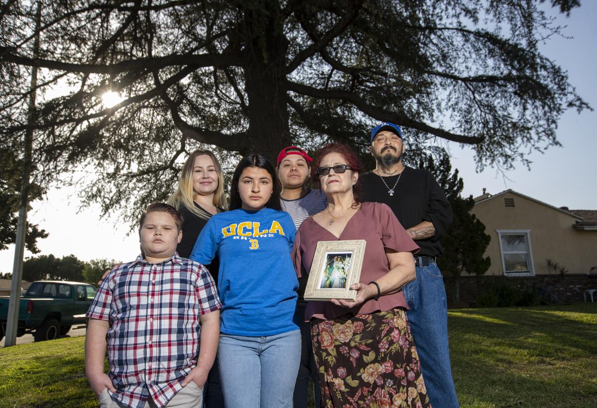 Jennifer Soto, in a UCLA shirt, is shown in Downey with her family, from left: Zack Pack; Rose Pack; Sara Bernard; Chris Bernard, holding her 1988 wedding photo of her and her husband, Alex Bernard; and Ismael Moreno.