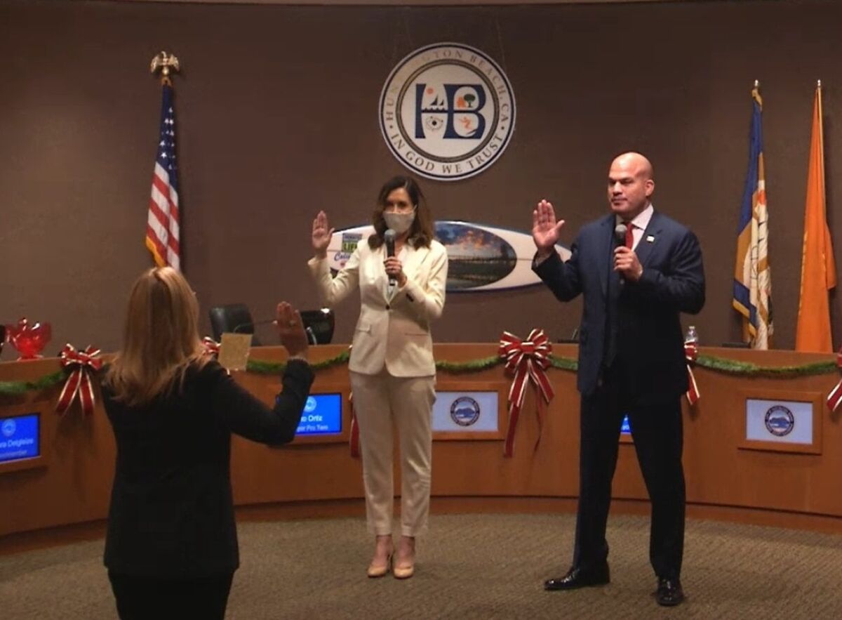 Huntington Beach City Clerk Robin Estanislau, left, swears in new Mayor Kim Carr and Mayor Pro Tem Tito Ortiz in December.