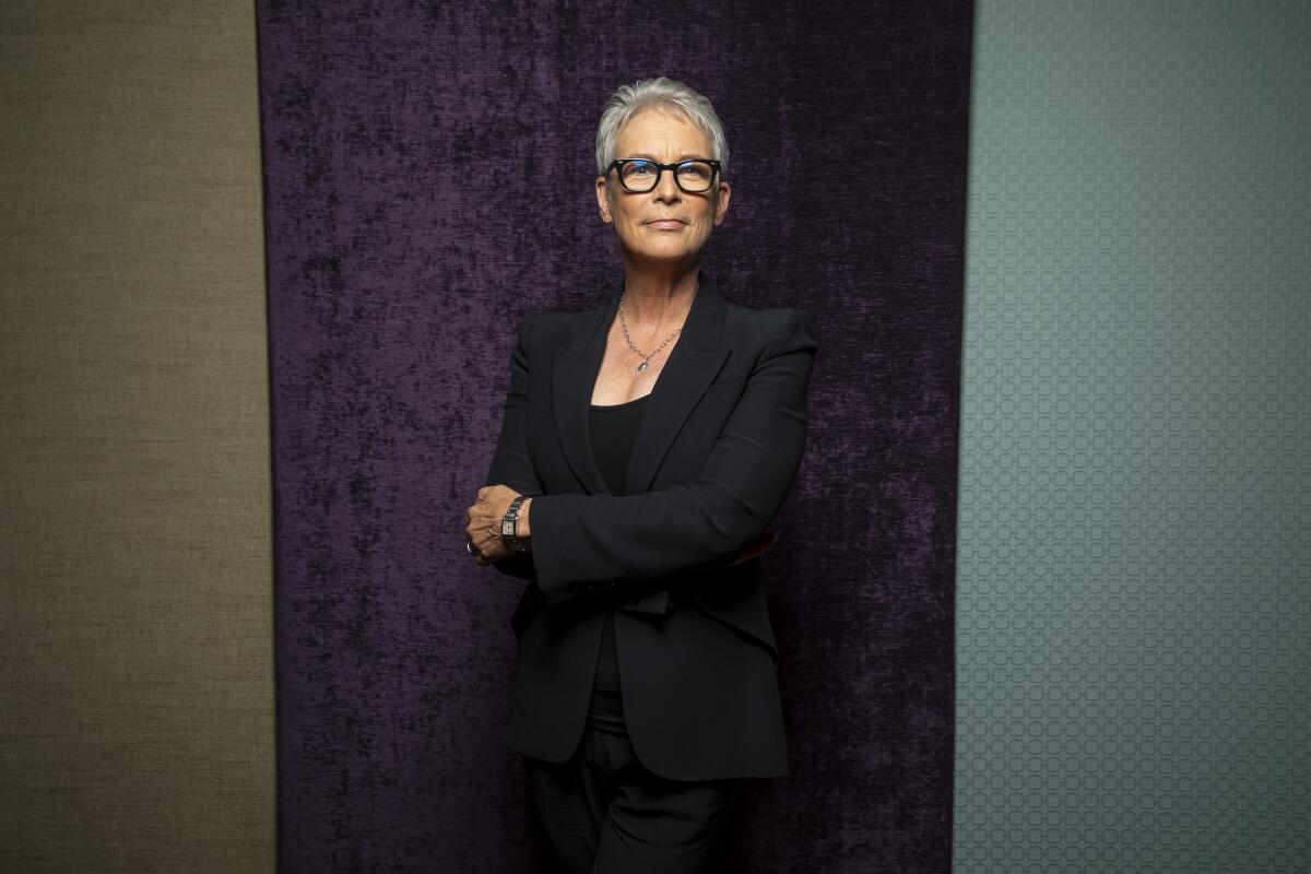 A woman with short gray hair and glasses poses for a portrait with her arms crossed.
