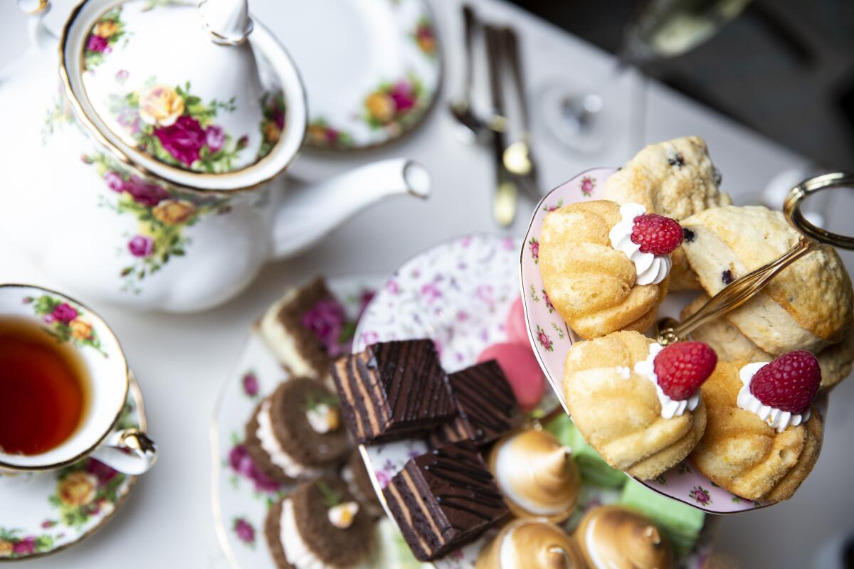 An overhead shot of a tiered tray of pastries, a floral teapot and teacup with a saucer.