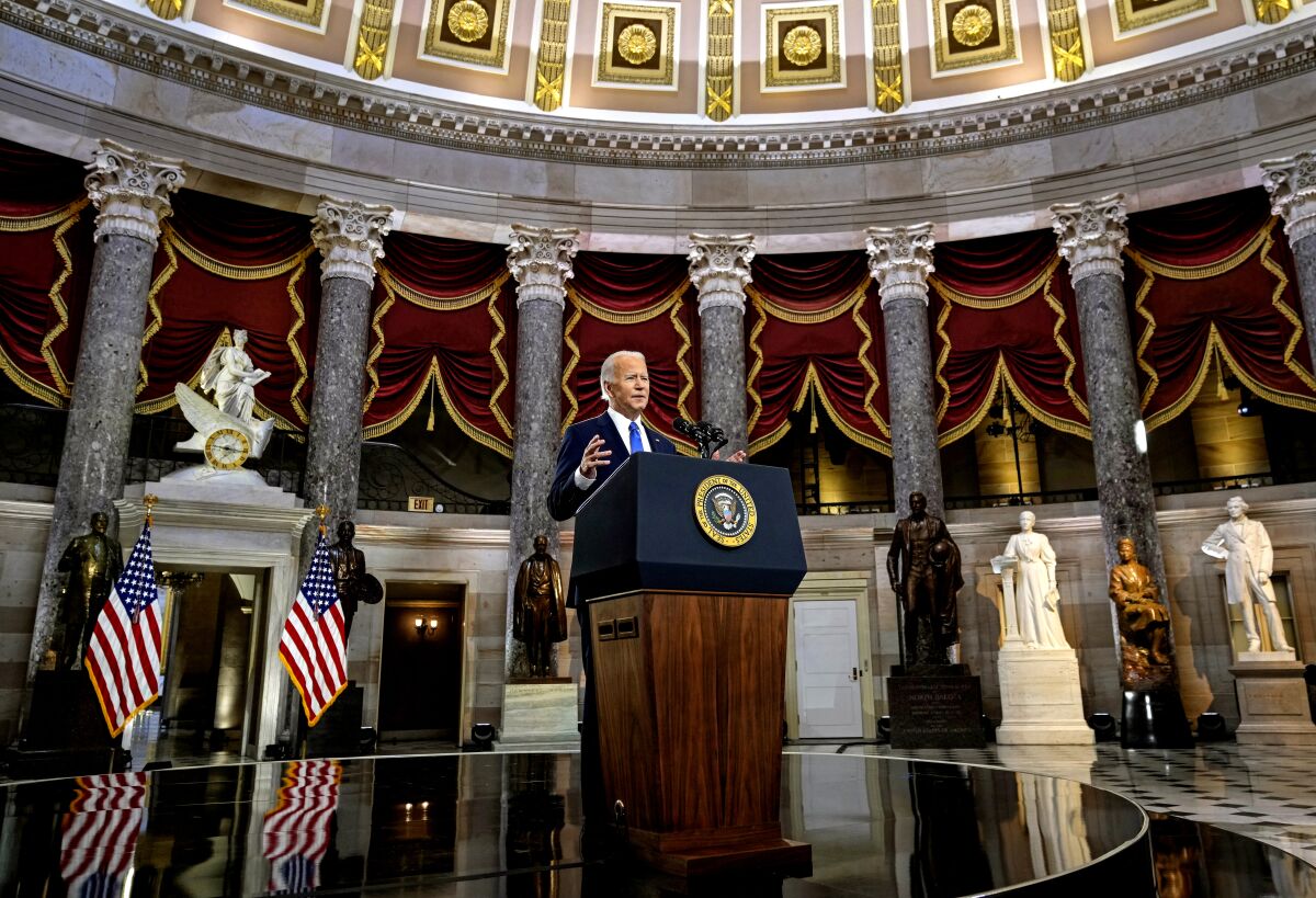 President Joe Biden stands at a lectern, surrounded by statues and pillars