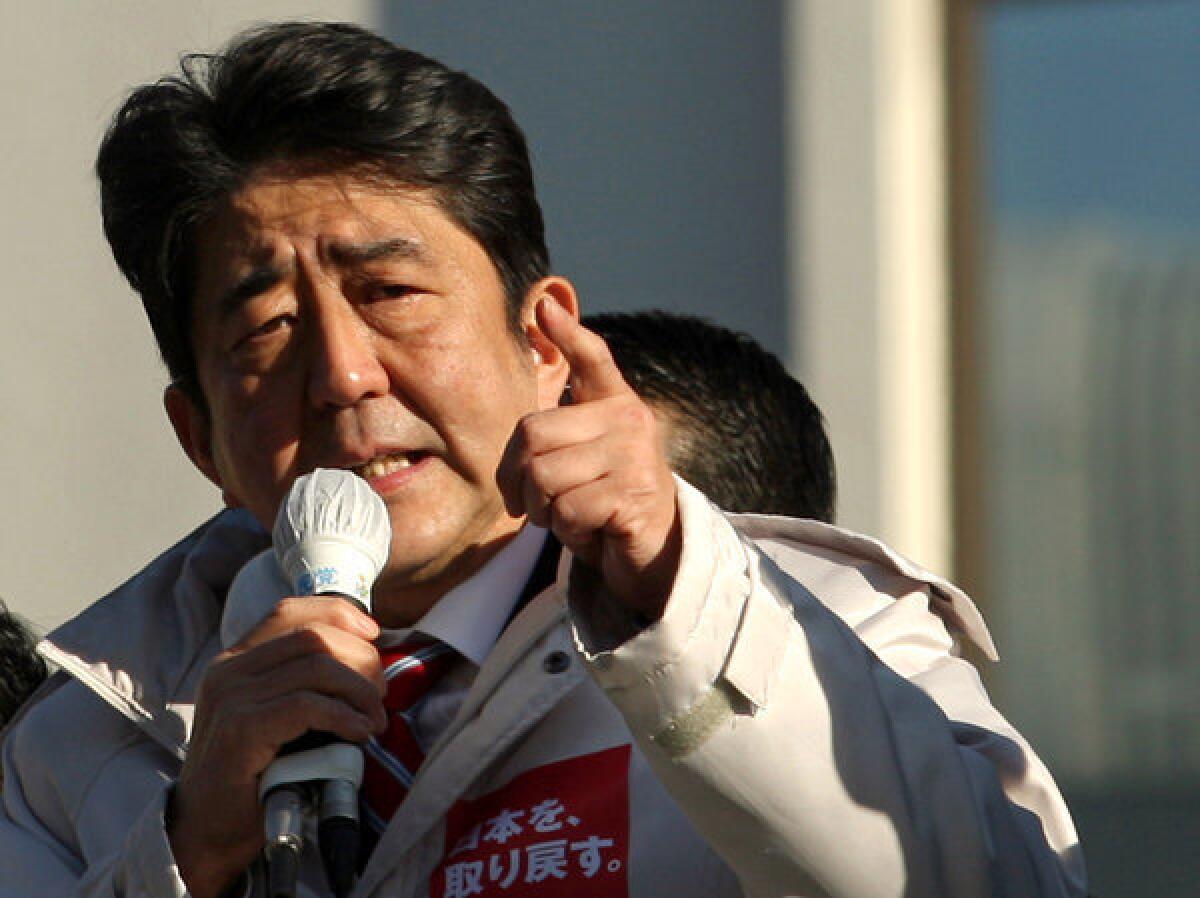 Former Prime Minister Shinzo Abe, leader of Japan's main opposition Liberal Democratic Party, gives a speech from the roof of a campaign car Thursday in Osaka, Japan.