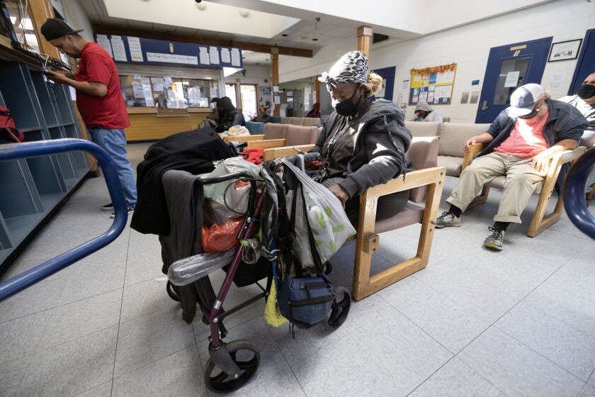 SAN DIEGO, CA - FEBRUARY 09, 2023: Brynda Howard, who lives in an Alpha Project shelter and is seeking housing, sits with her walker while Roberto Silva, left, checks his phone that's being charged in the day room at the Neil Good Day Center in San Diego on Thursday, February 09, 2023. (Hayne Palmour IV / For The San Diego Union-Tribune)