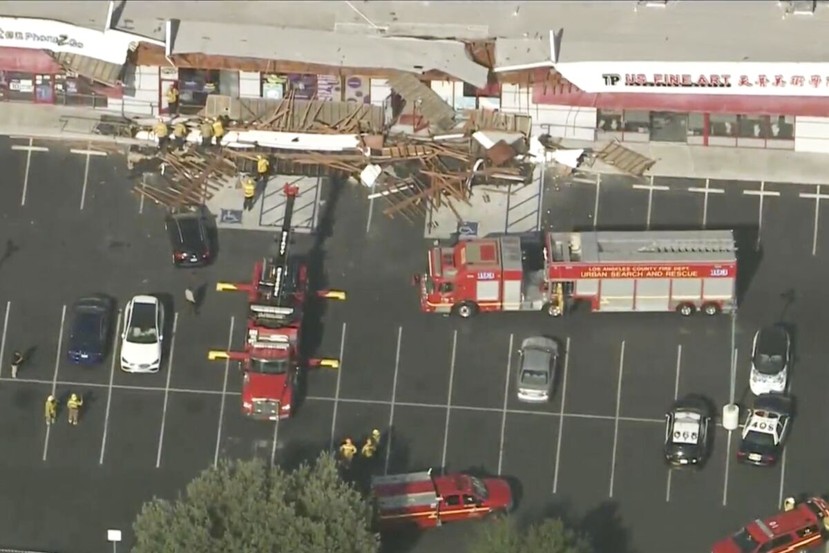 Aerial view of firetrucks outside a building with a collapsed facade and debris blocking the entrance