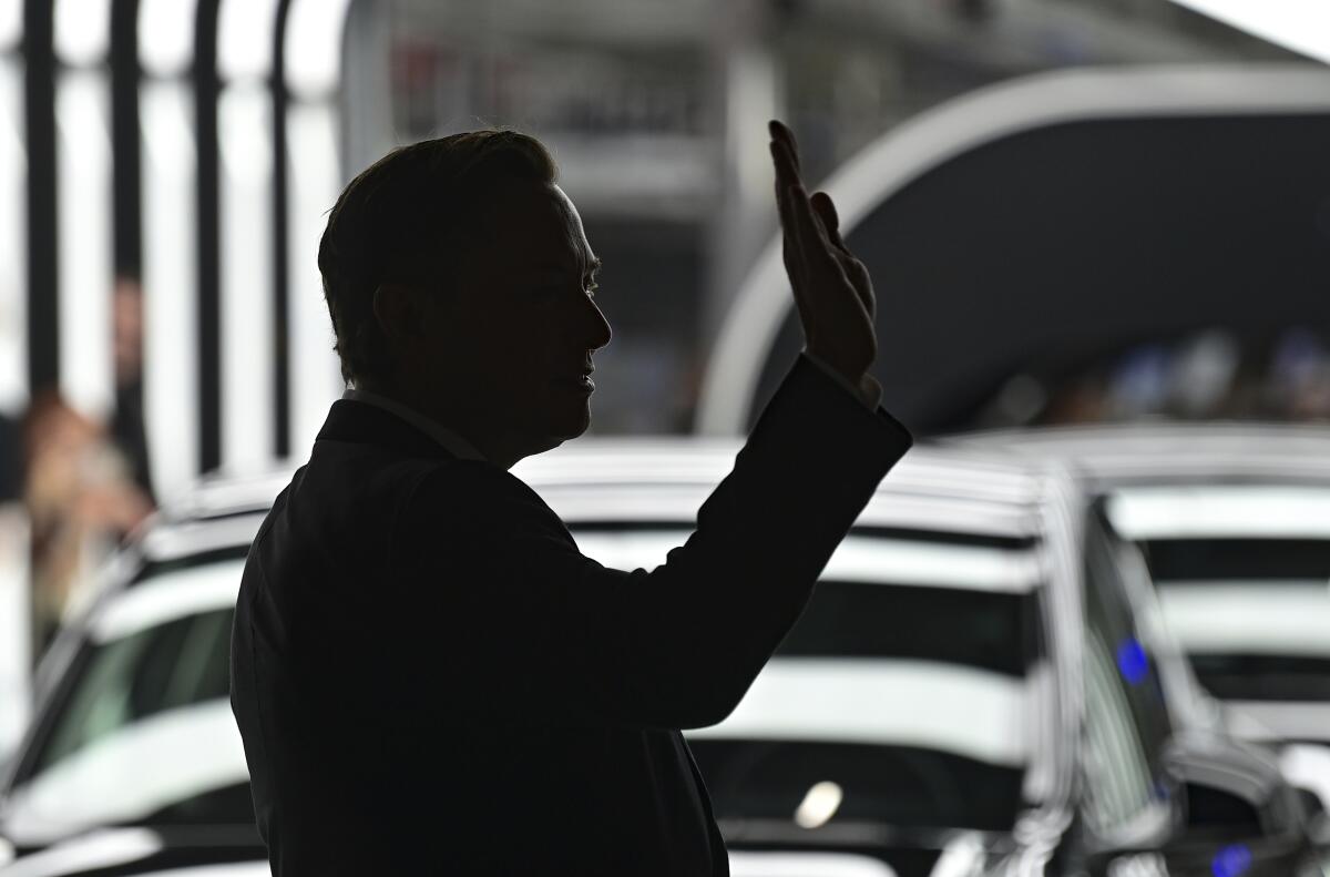 Elon Musk, in shadow, waves at the opening of Tesla's factory near Berlin. 
