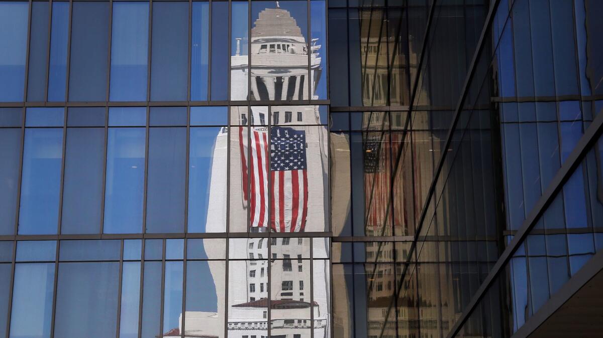 The American flag draped on Los Angeles City Hall is reflected in the windows of LAPD headquarters in September.